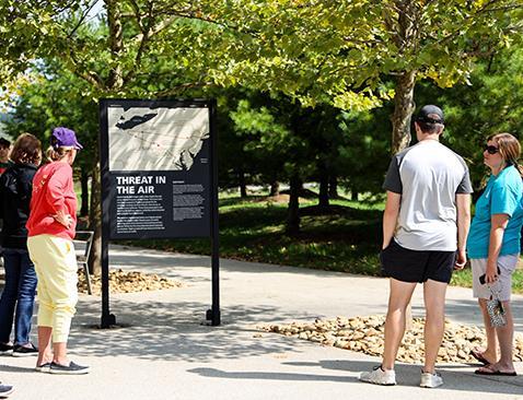 People standing around looking at a plaque that says 