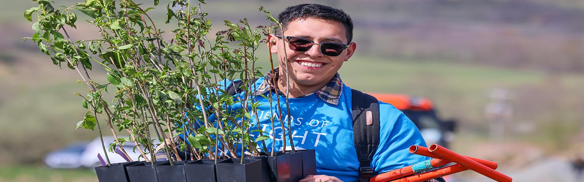 Volunteer holding small trees to plant