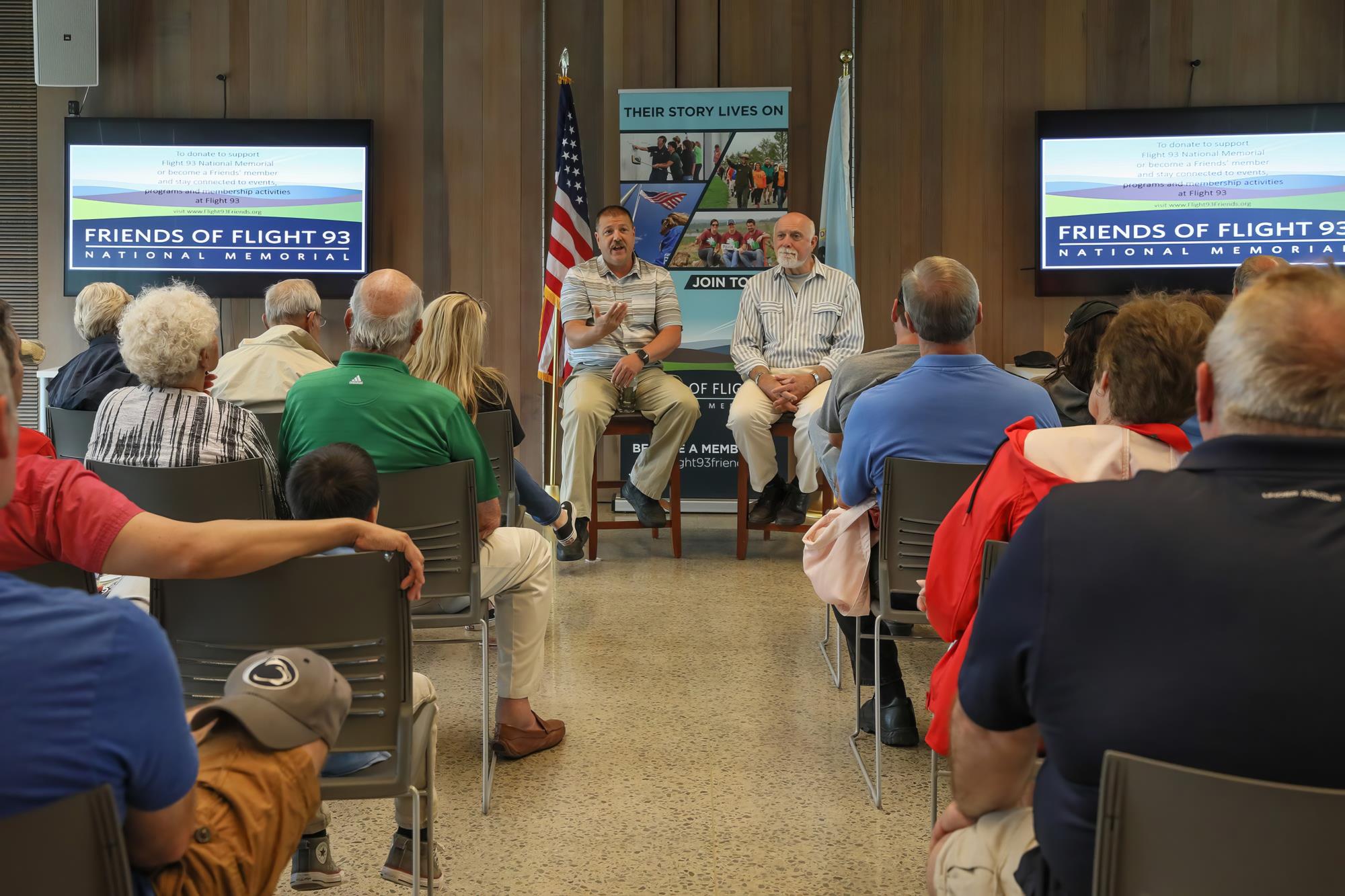 Two people at the front of the room speaking to a room full of people