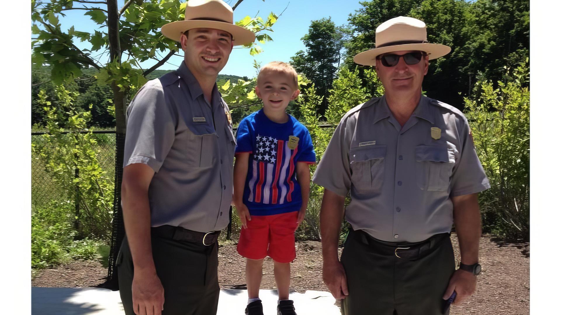 Two National Park workers standing with a kid