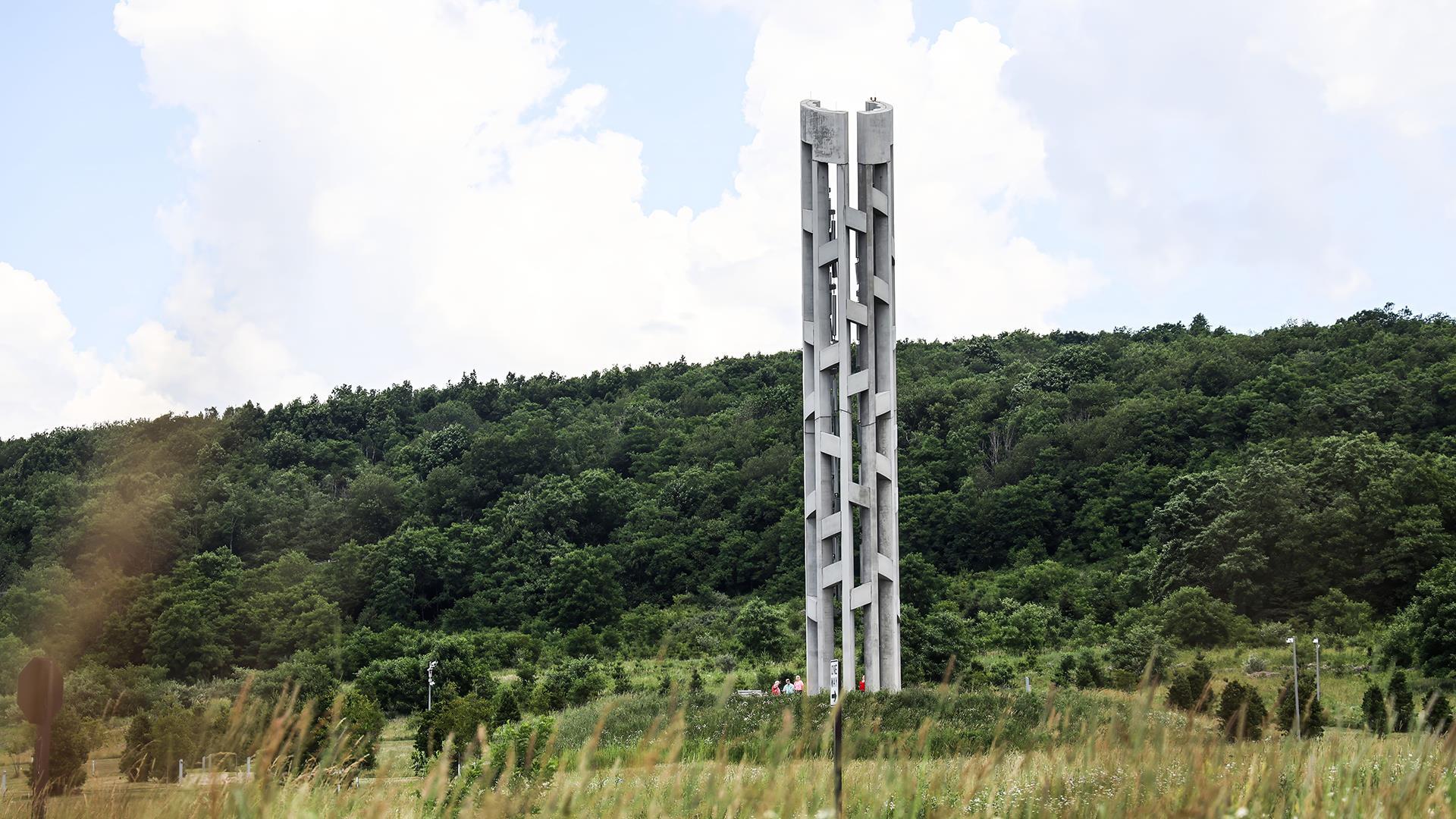 a memorial tower with a green mountain behind it