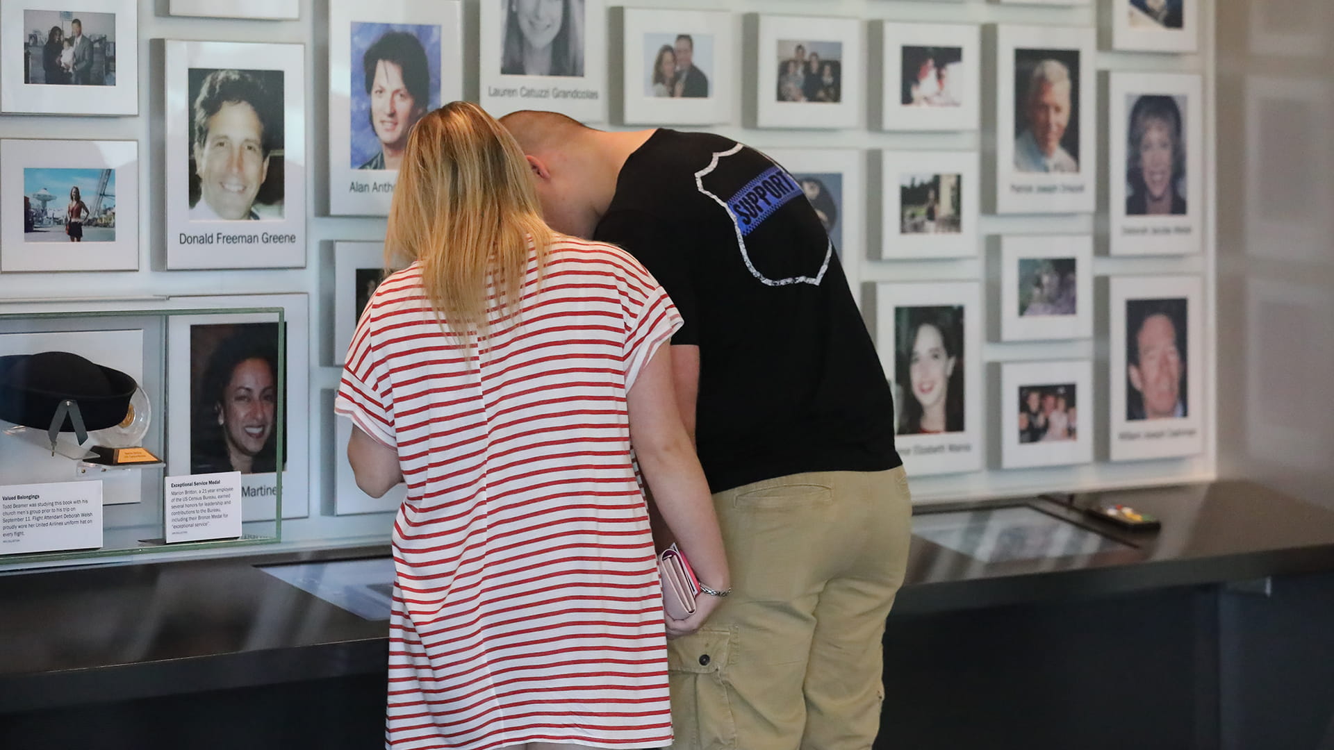 Couple looking at photos displayed on a wall.